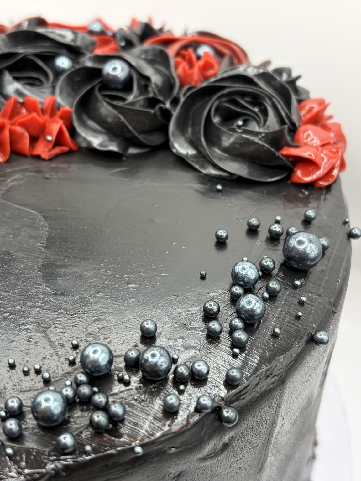 Black and red cake detail with metallic sugar pearls