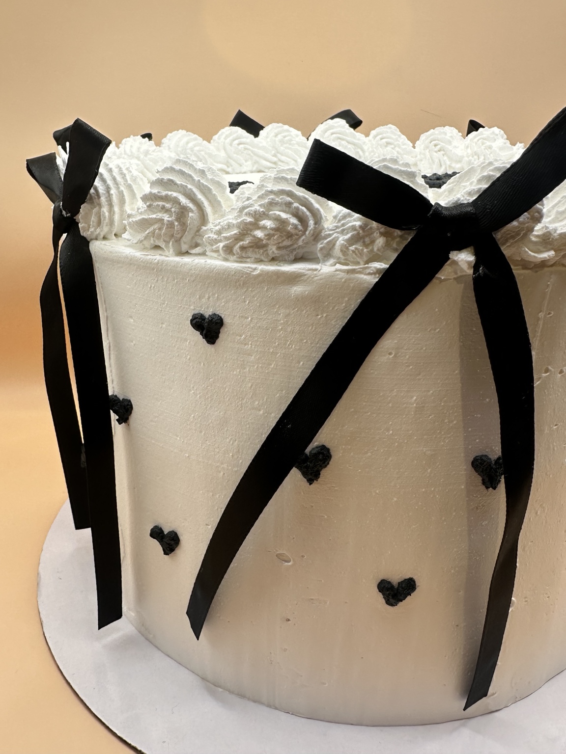 White cake with black hearts and ribbon bows