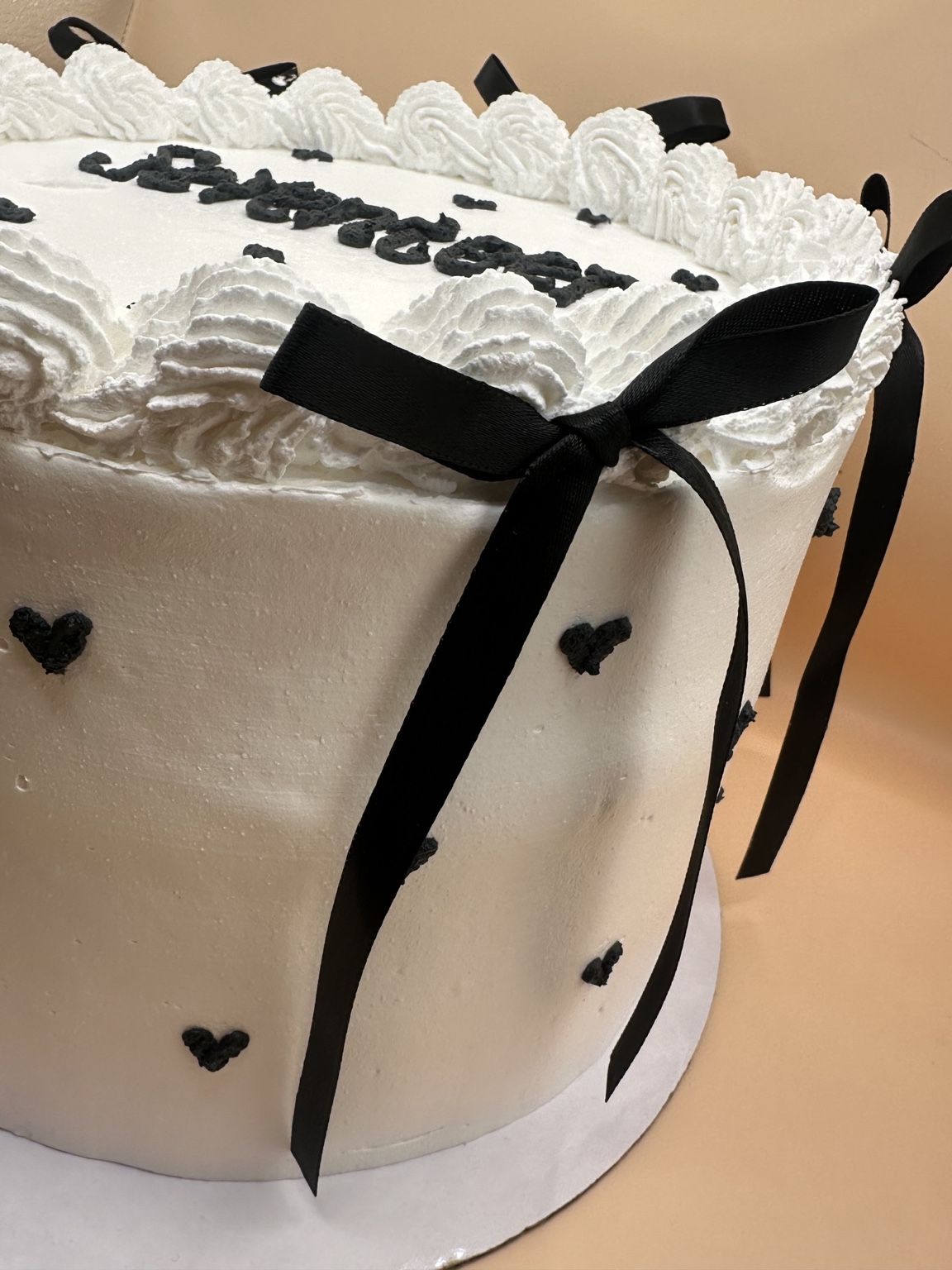 White heart cake detail with black ribbon bow